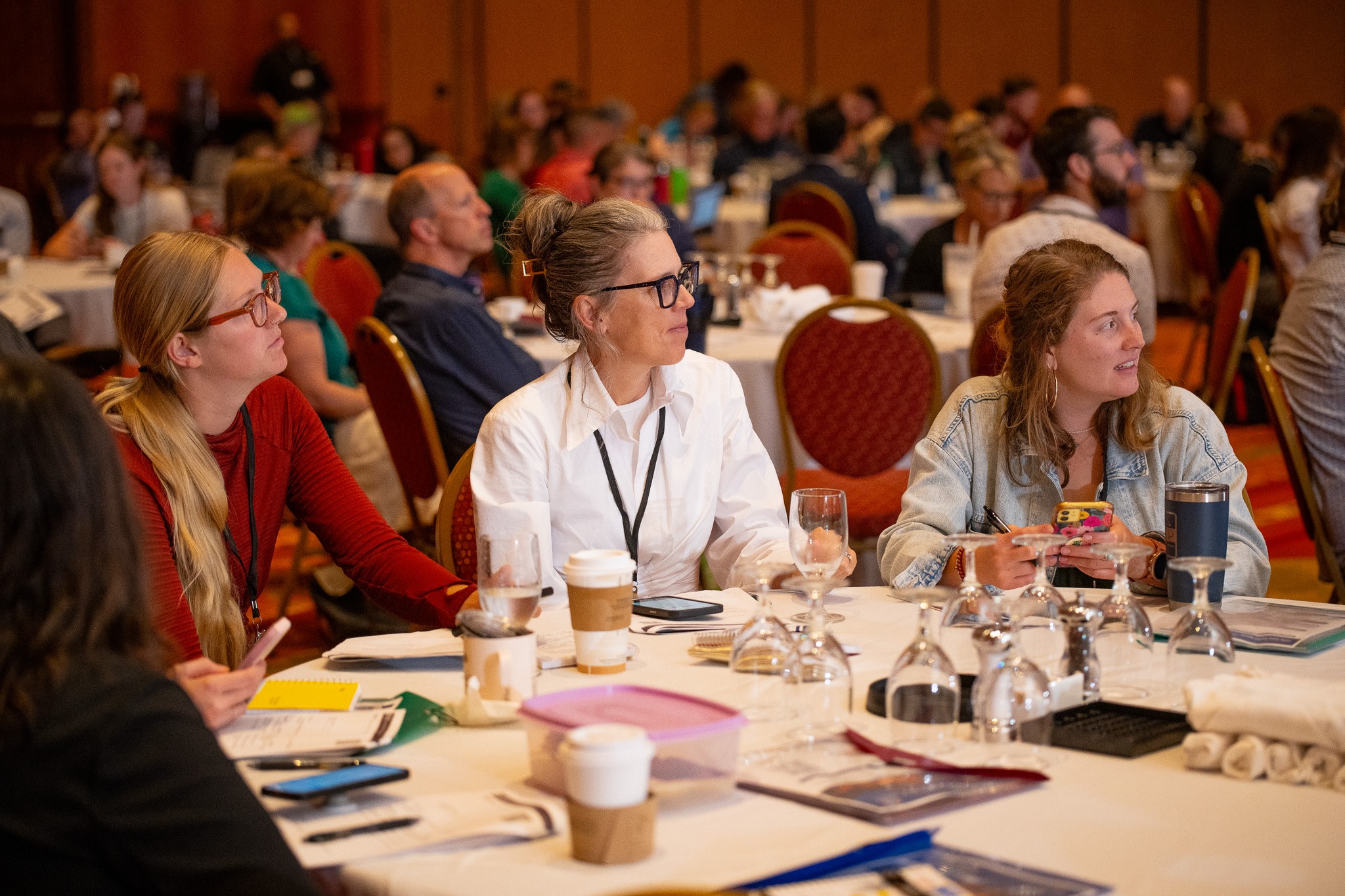 A group of professionals sit around a table listening to someone speaking out of the frame.