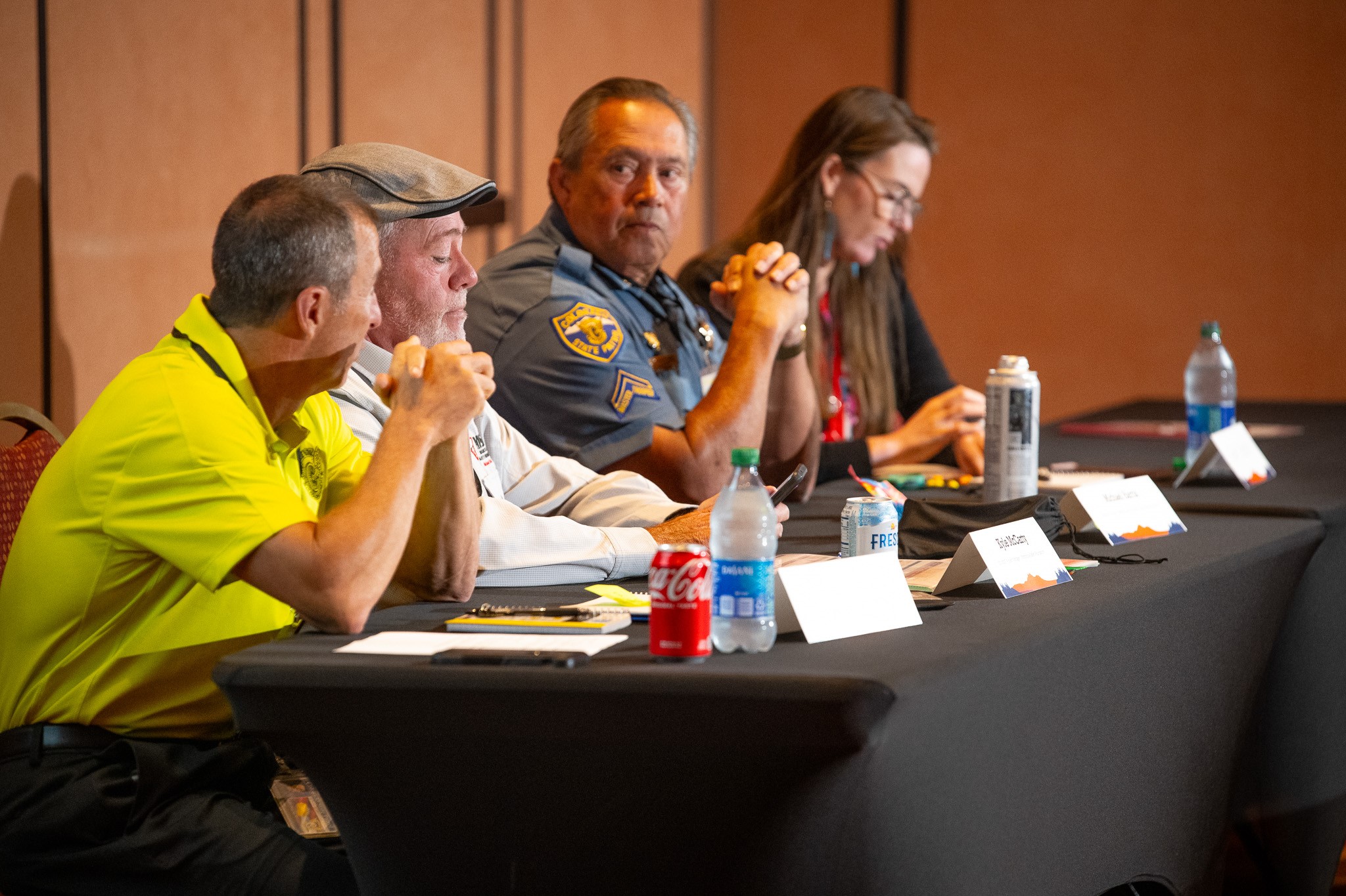  Four experts sit on a panel. One is wearing a law enforcement uniform. 